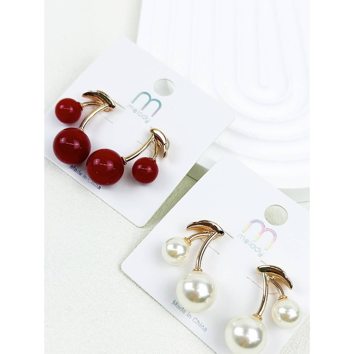 Cherry-themed earrings on a white card with visible brand name.