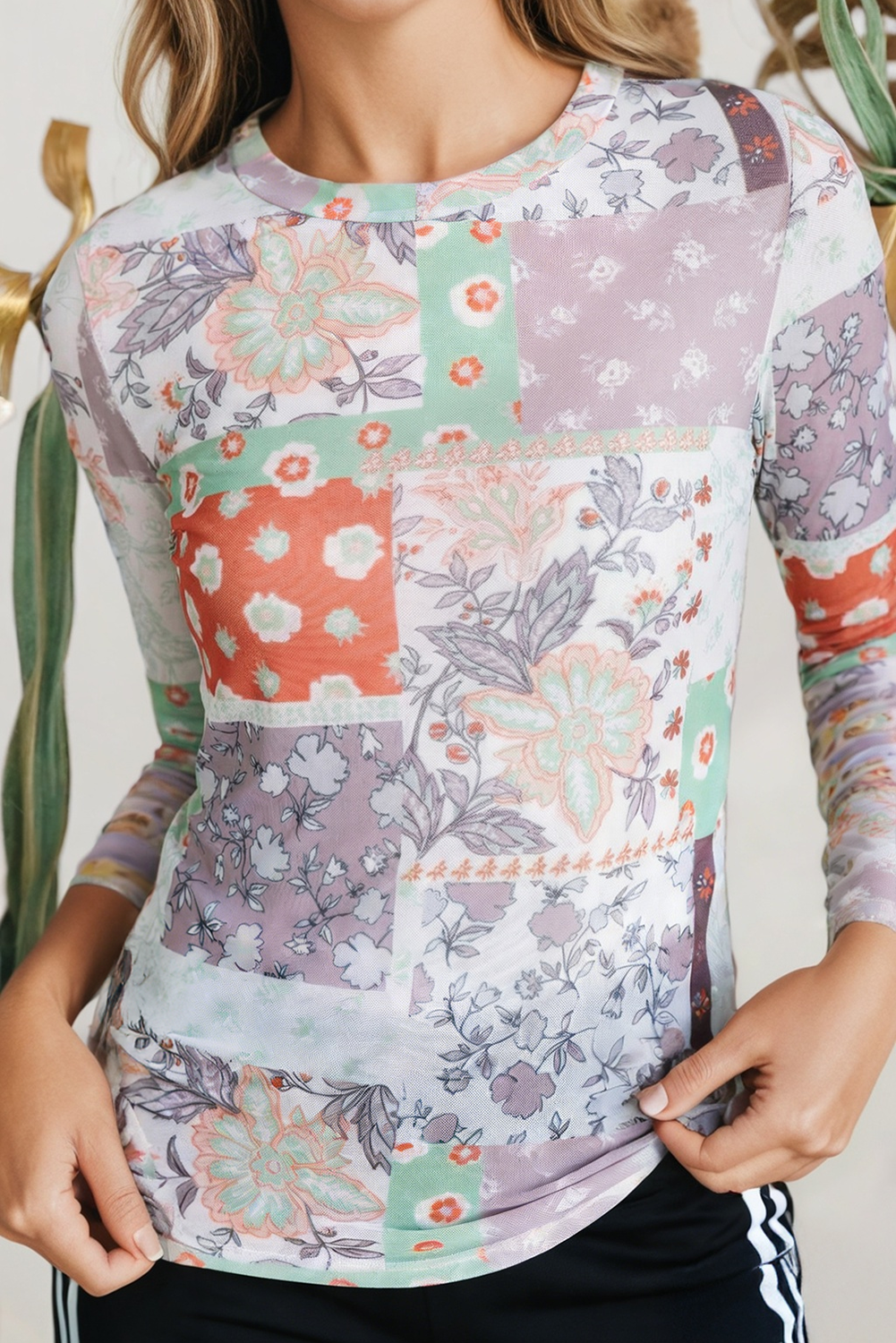 Woman wearing a colorful patchwork floral top with a neutral background