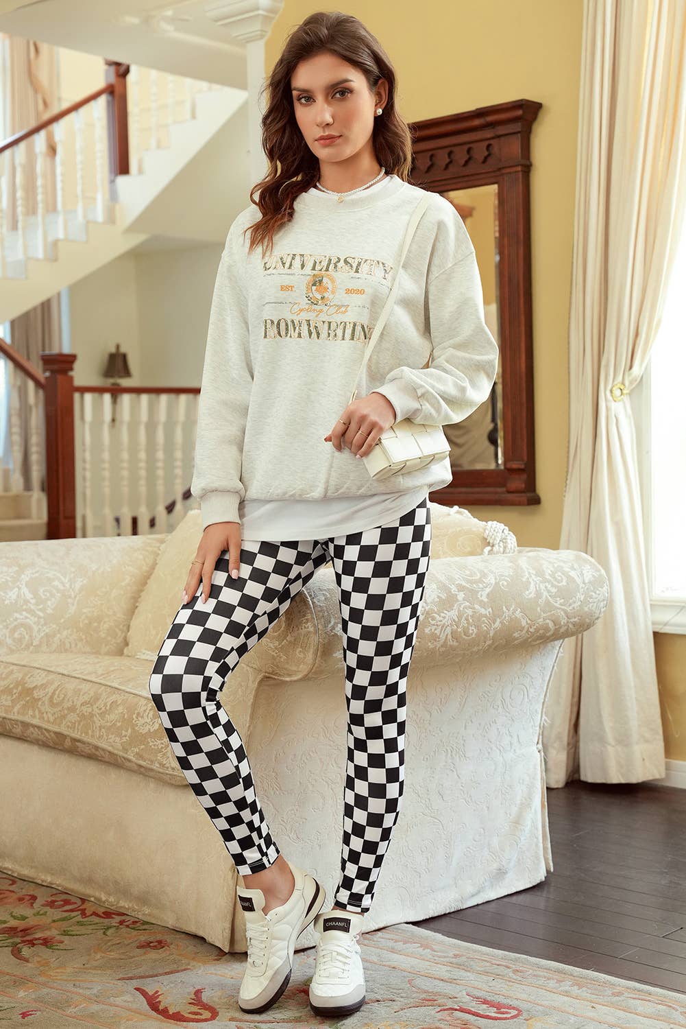Woman wearing a white sweatshirt and checkered pants in a living room.