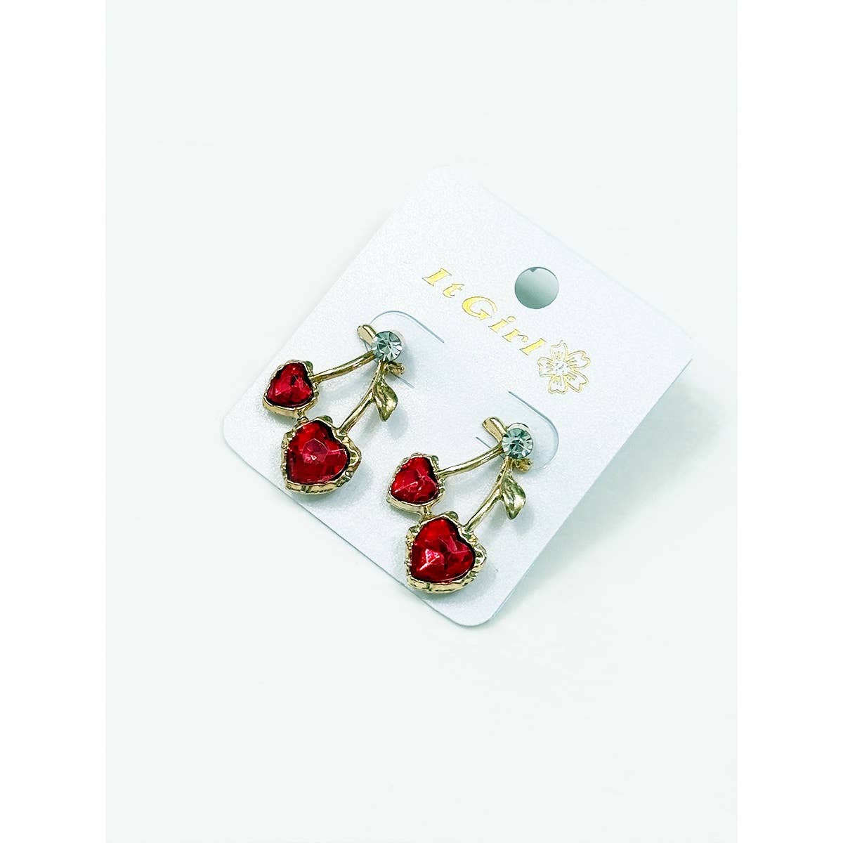 Red heart-shaped earrings on a white card with 'Le Glitter' branding.