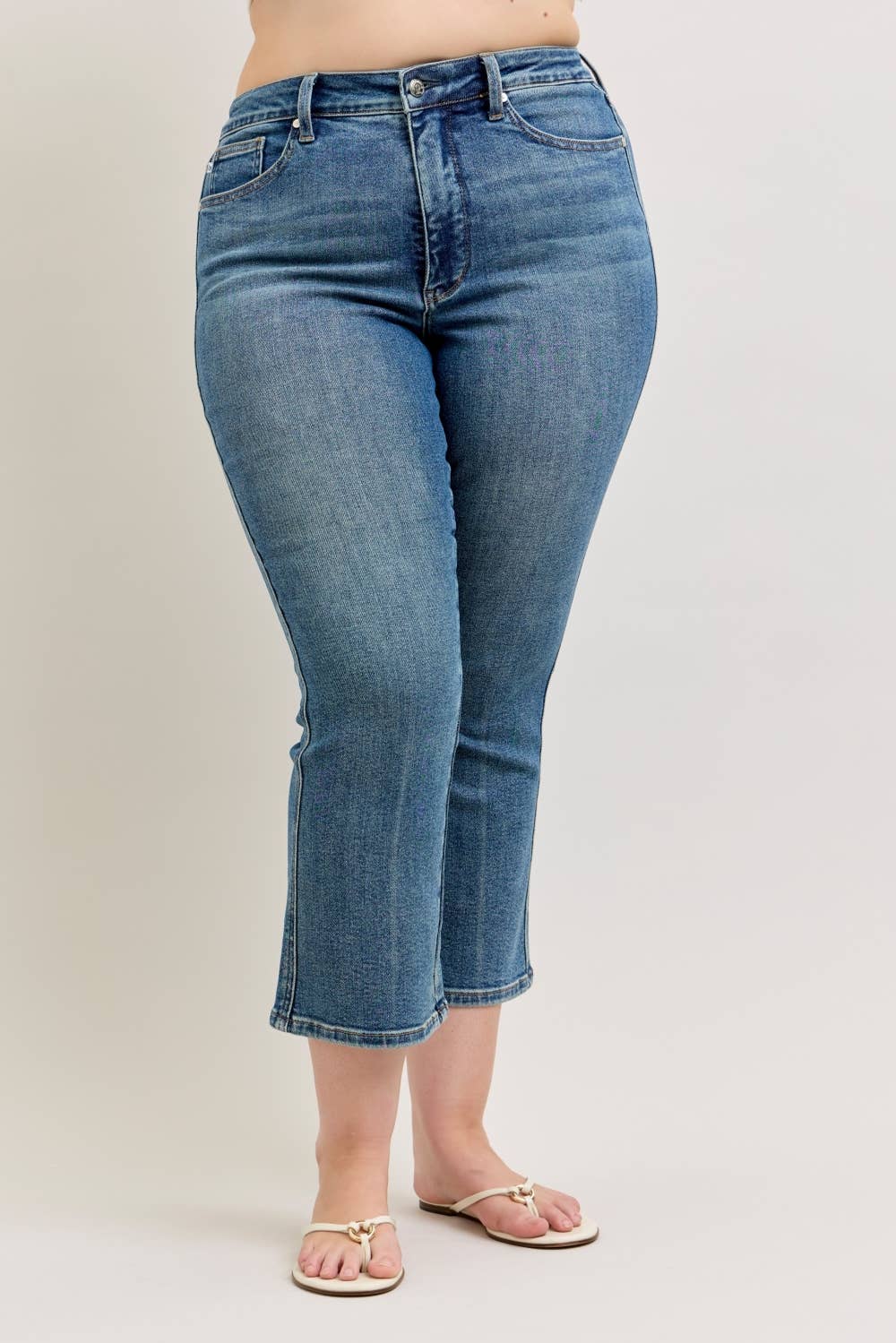 Blue jeans worn by a person on a plain background