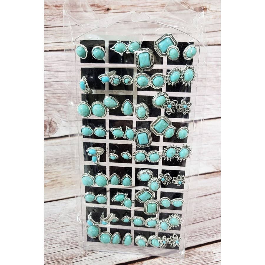 Set of turquoise and silver earrings in a clear plastic case on a wooden surface