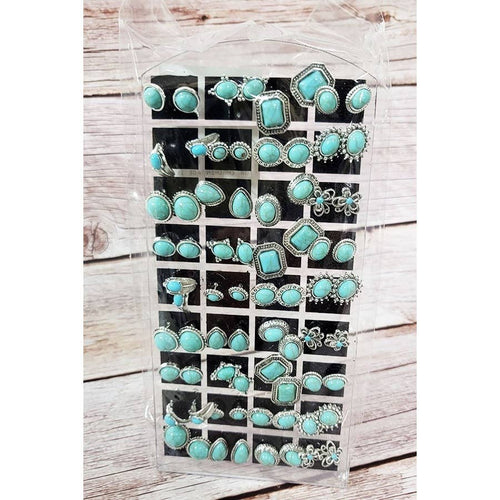 Set of turquoise and silver earrings in a clear plastic case on a wooden surface