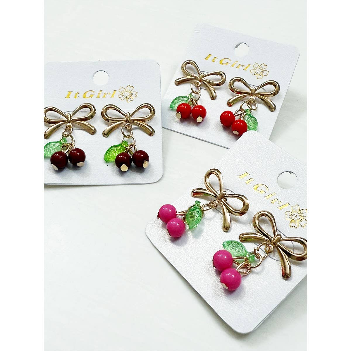 Pair of earrings with bow and berry design on branded card