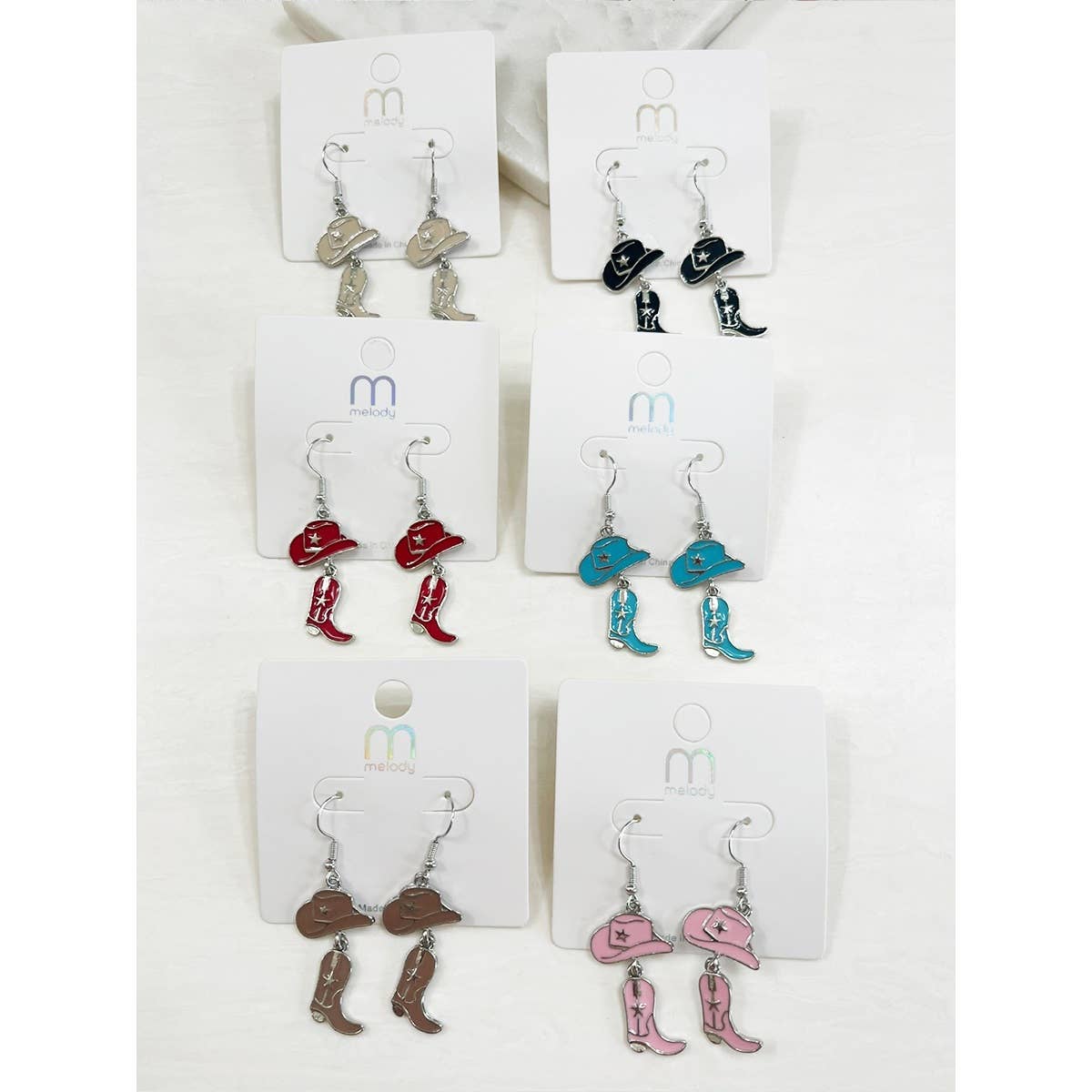 Set of earrings on display cards with various designs including hats, boots, and cowboys.