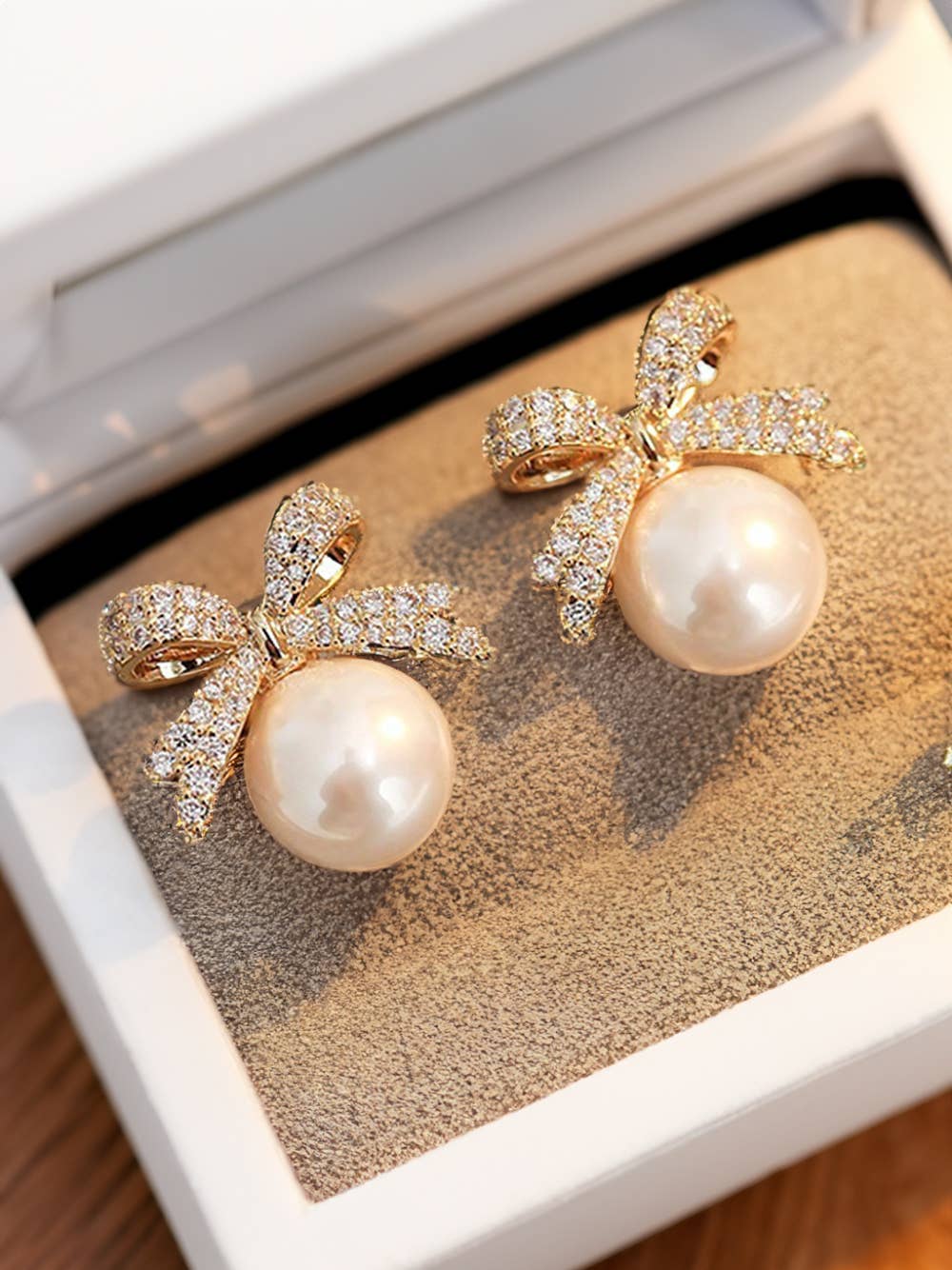Pearl earrings with bow designs on a textured surface