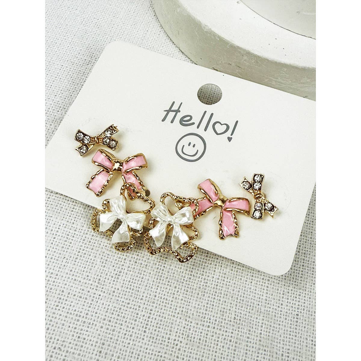Pair of earrings with pink and white bows on a 'Hello!' card.